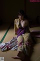 A woman in a kimono sitting on a tatami mat.